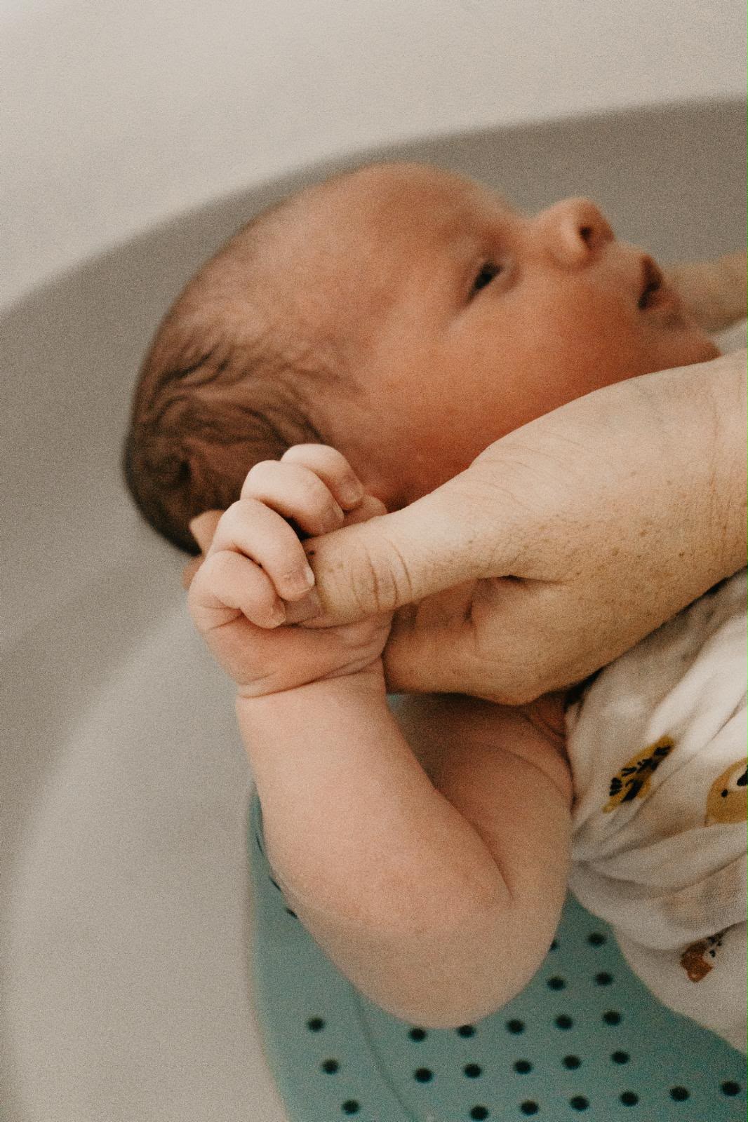 Nouveau-né tenant la main de sa maman pendant le bain sensoriel