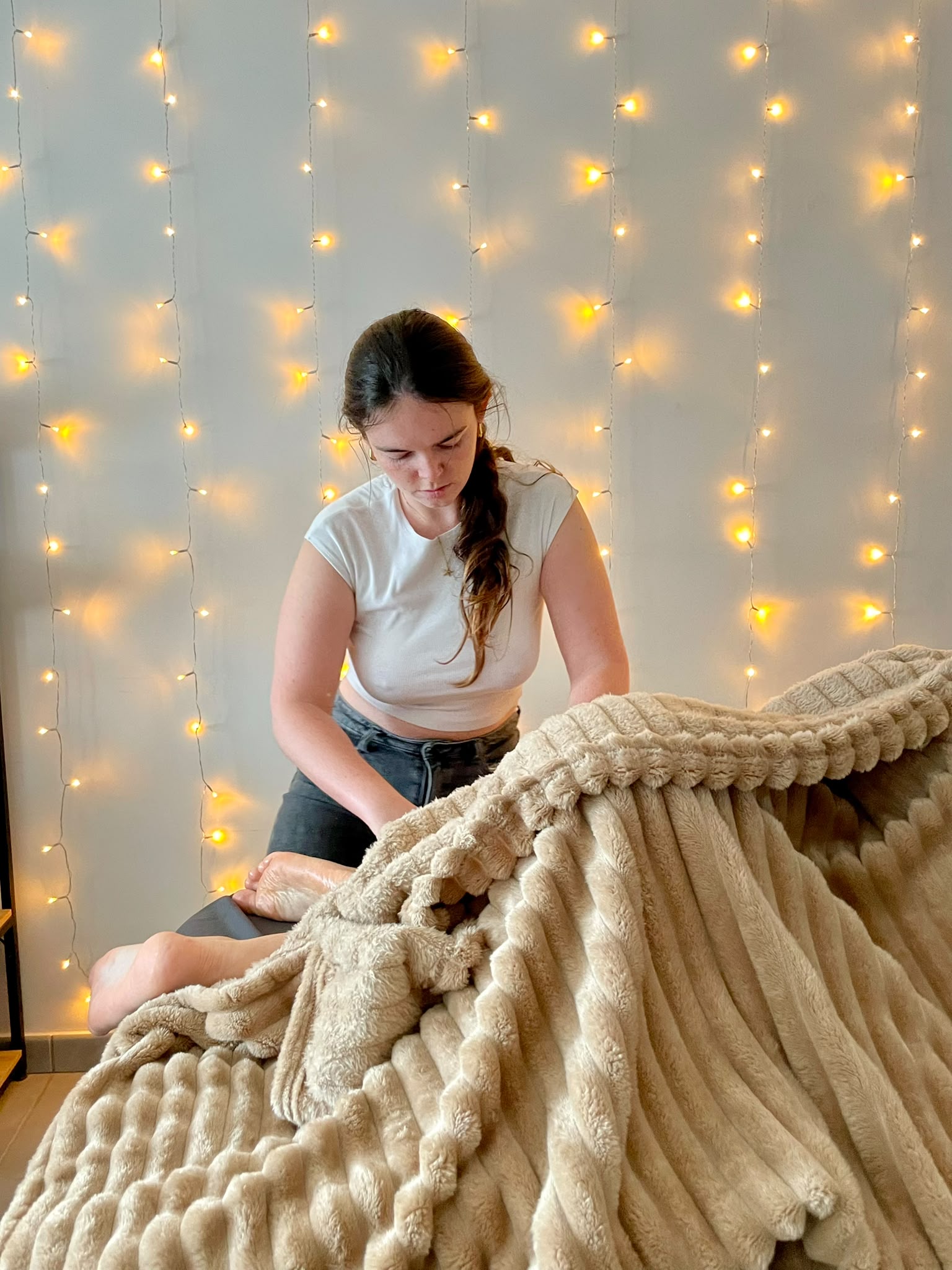 Elisa Pelon réalisant un massage sous une guirlande lumineuse