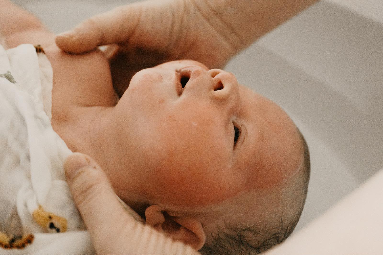 Bébé apaisé, tenu avec douceur lors du rituel du bain sensoriel