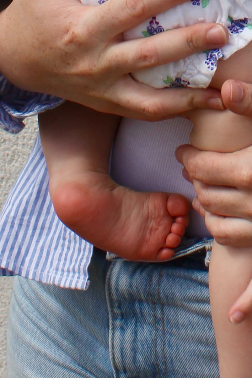Mains posées délicatement sur les pieds d'un bébé lors d'une séance de réflexologie